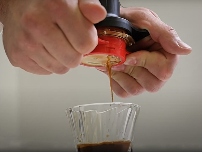 Two hands manually pulling a fresh espresso shot using the Cafflano Kompresso