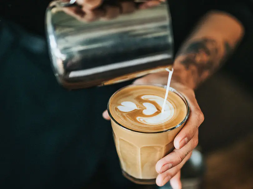 Making a magic coffee by pouring freshly steamed milk onto a double ristretto