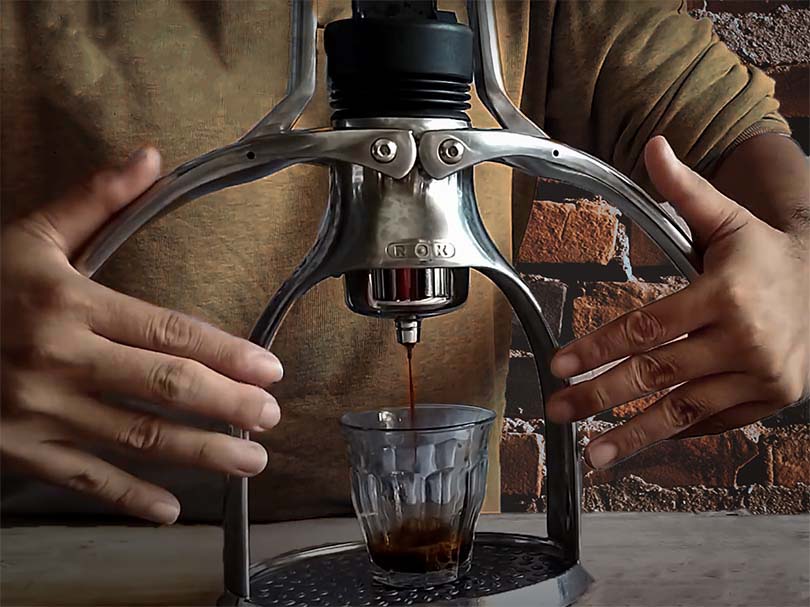 Hands pulling down the manual levers on the Rok Espresso GC