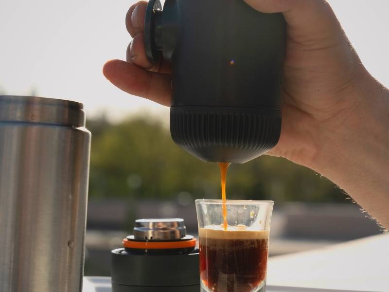 Wacaco Nanopresso in my hand, pressing piston, and pulling a fresh shot of espresso into waiting glass