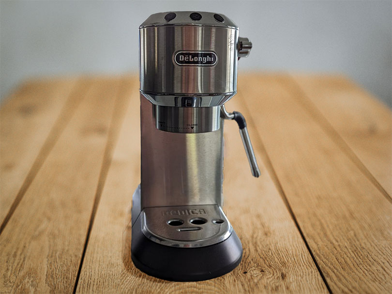 DeLonghi Dedica Arte espresso machine sitting on a wooden table
