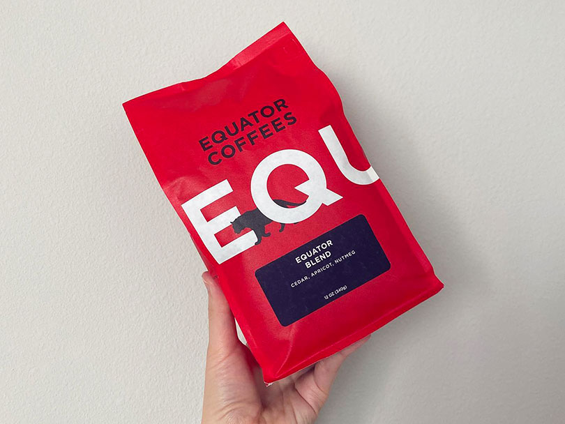 Equator Coffees - Equator Blend being held against white wall
