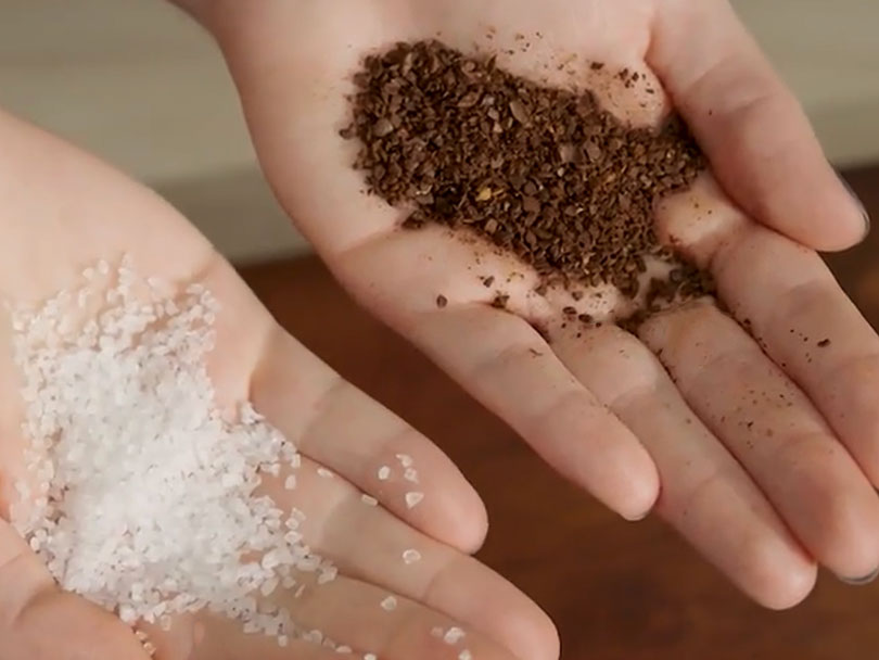 Coarse sea salt in one hand and coarse ground coffee in the other