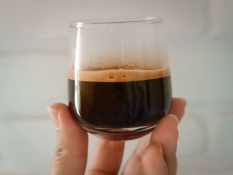 Holding a shot of espresso up to the camera