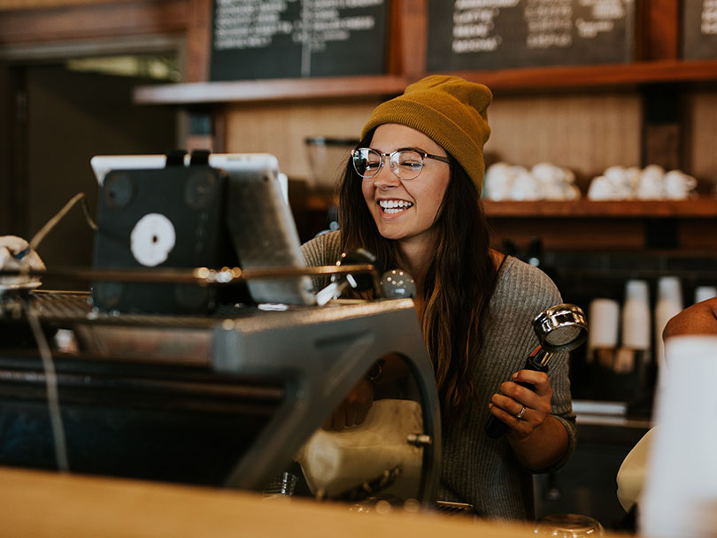 A smiling barista working in an artisanal third wave coffee shop