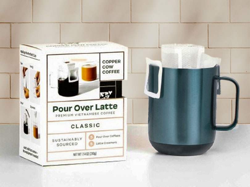 Box of Copper Cow Coffee pour over latte set beside a cup with pour over coffee bag on it