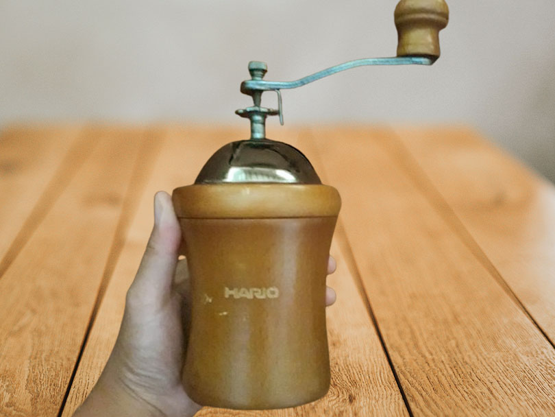 Hario "Dome" Ceramic Coffee Mill held in man's hand towards camera