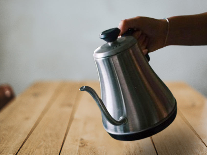 Holding Willow & Everett Gooseneck Kettle above a wooden table