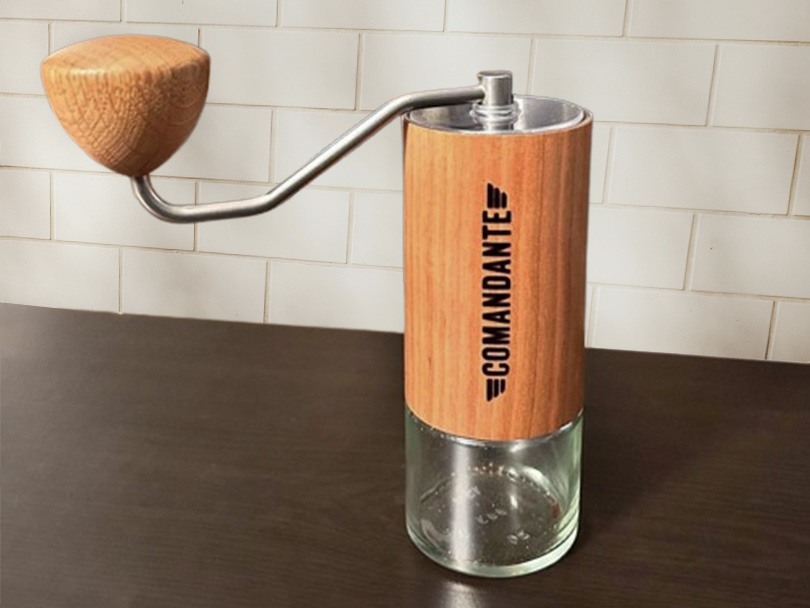 Comandante C40 MK4 hand grinder in American Cherry sitting on wooden countertop