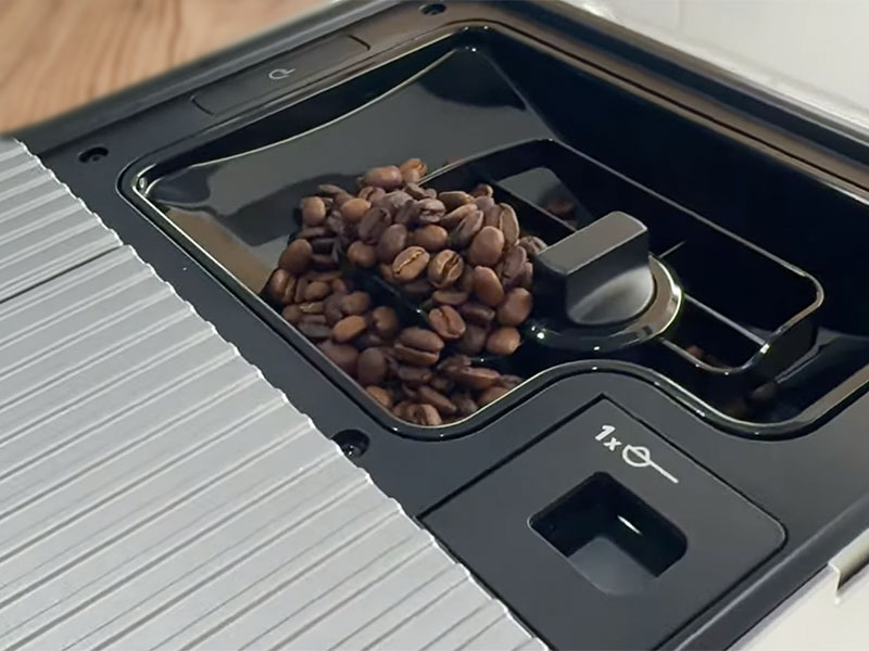 Close up of the KitchenAid KF7's bean hopper with beans in it, and a separate pre-ground coffee chute