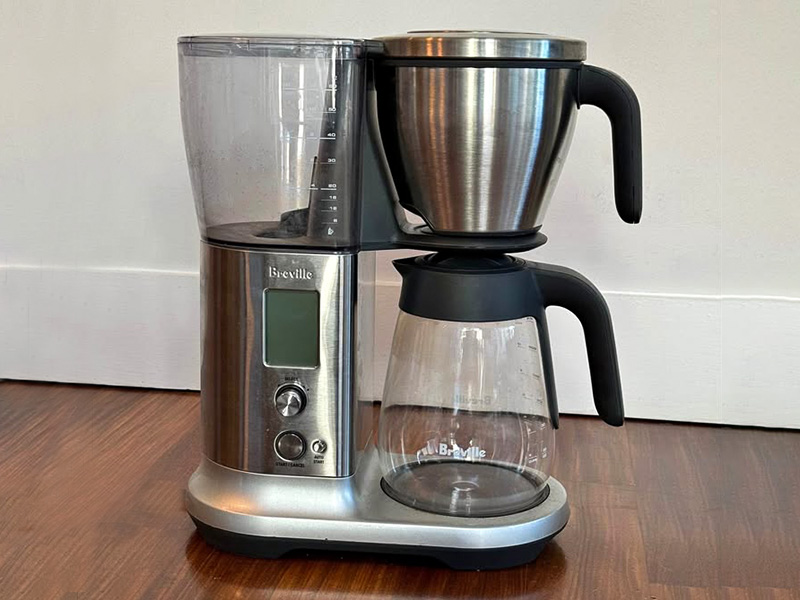 Breville Precision Brewer on wooden work surface with white wall behind it