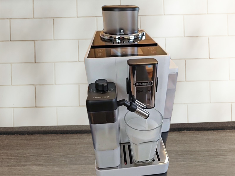 Front view of the DeLonghi Rivelia dispensing milk into a waiting glass