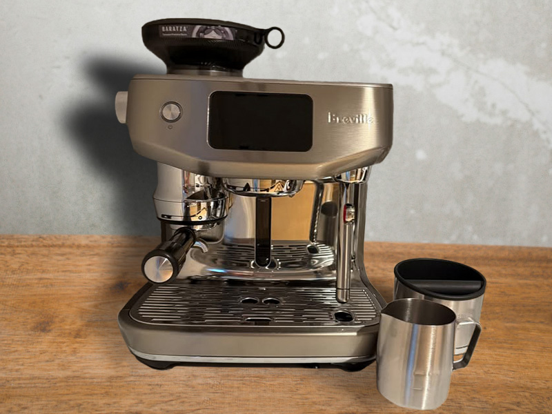 Front view of the Breville Oracle Jet with milk jug and knock box