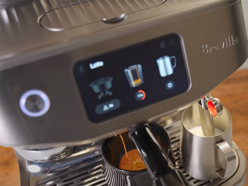 Top down view of the Breville Oracle Jet making a latte - pouring espresso whilst milk jug waits under the milk wand