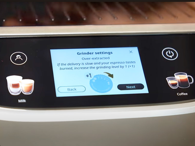 Close-up of the DeLonghi Magnifica Plus' touchscreen explaining grinder settings and over-extracted coffee