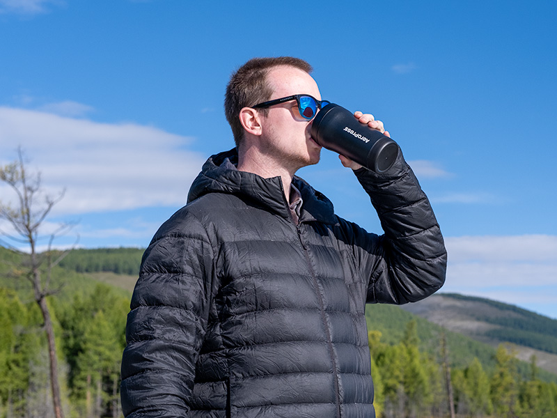 Man drinking freshly brewed coffee from the AeroPress Go Plus travel cup whilst camping