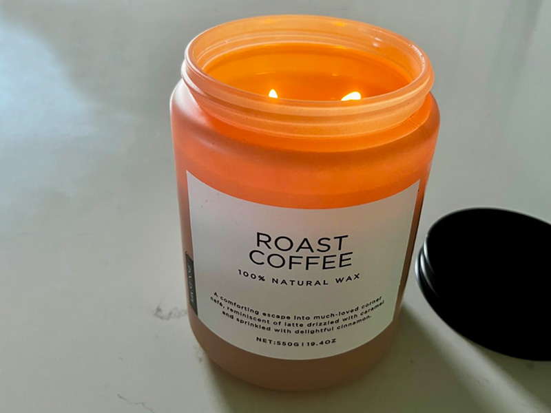 Large orange roast coffee candle burning on countertop