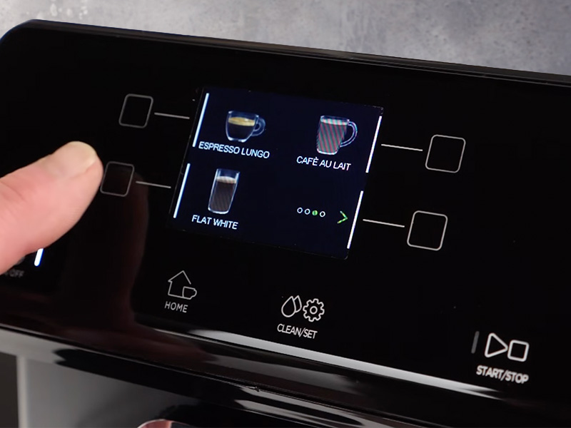 FInger pointing at the Gaggia Magenta Prestige's user interface scrren showing espresso lungo, cafe au lait and flat white options