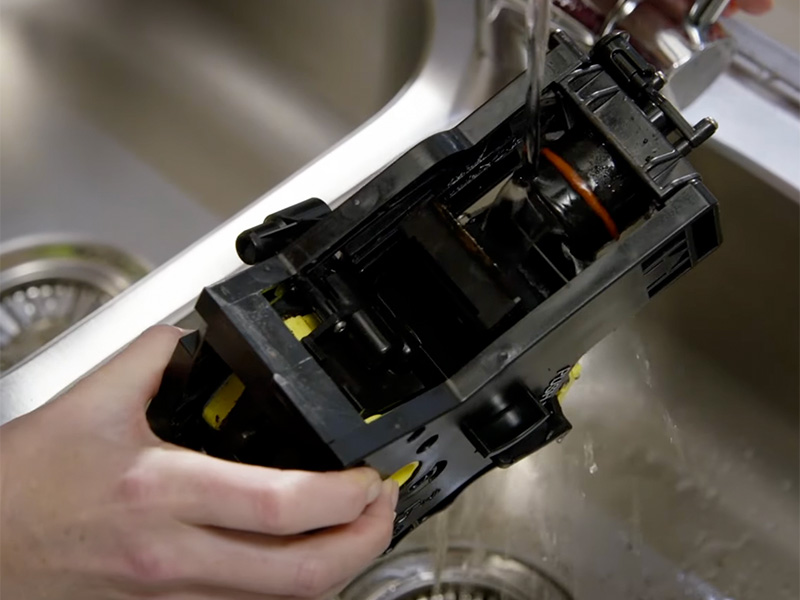 Rinsing the brew group of a Philip espresso machine under the faucet