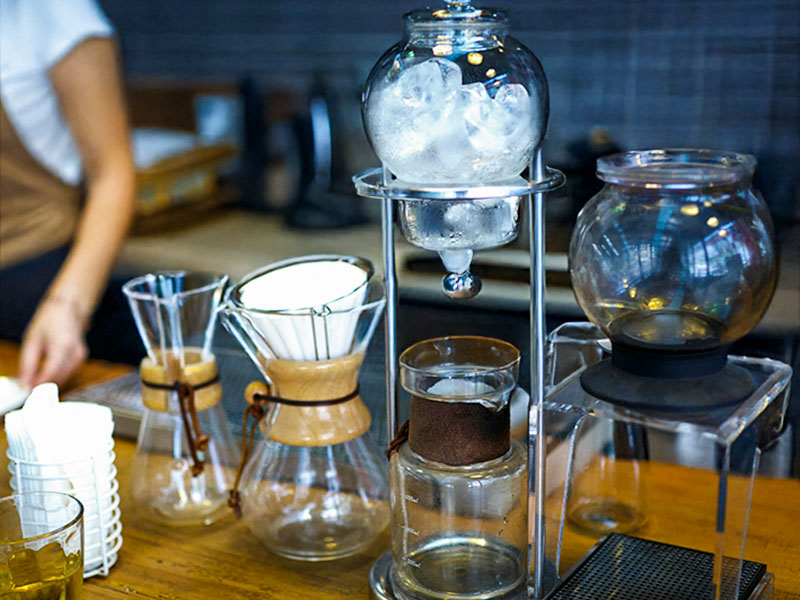 Coffee station with different types of coffee maker including 2 siphons and 2 manual drip brewers