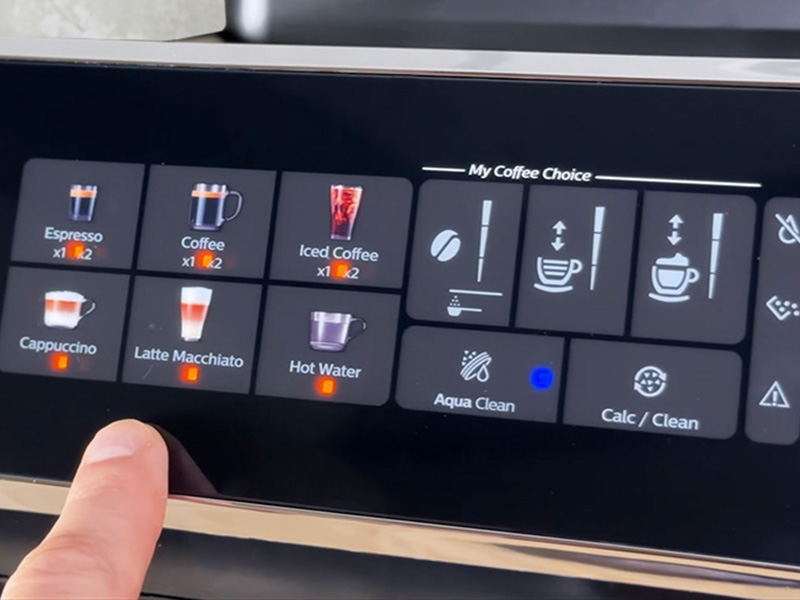 Finger pointing out to the Philips 3300 screen with lights over the drinks selections