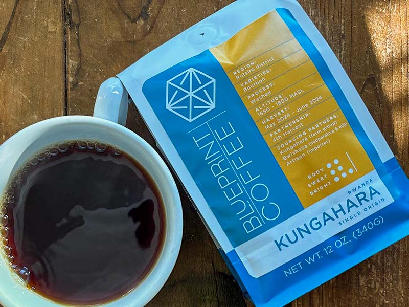 Bag of Rwanda Kungahara coffee beans from Blueprint Coffee, with a cup of freshly made coffee (pour over) beside it