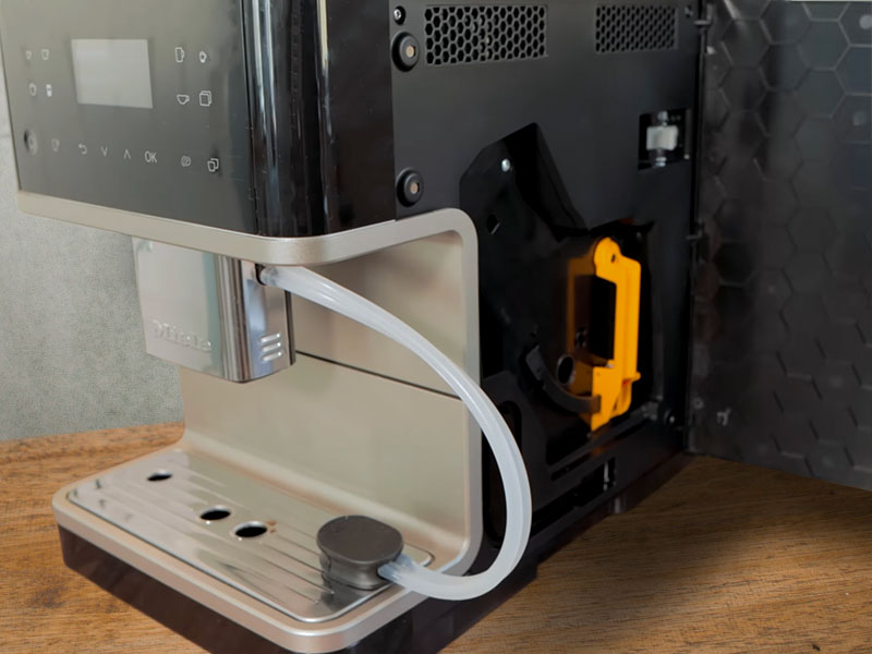 The side panel of the Miele CM 6360 opened to reveal the removable brew unit