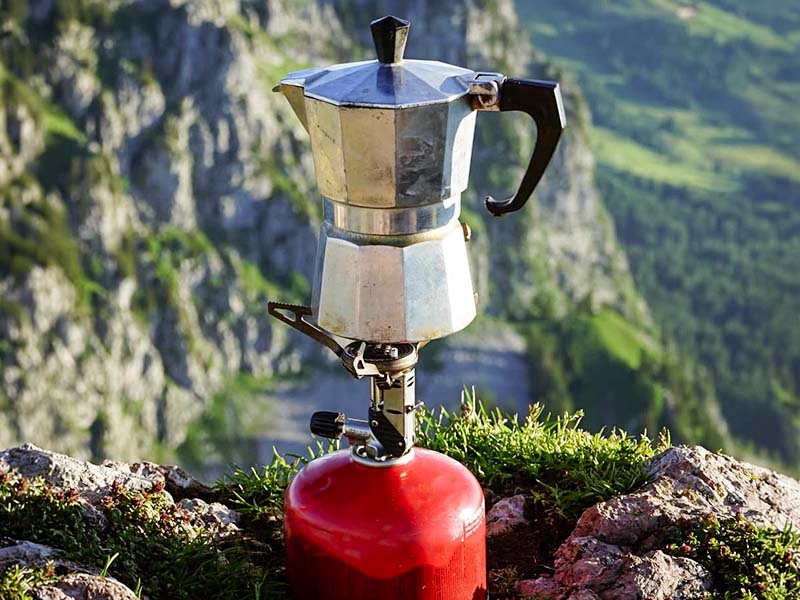 A Bialetti Moka pot on a camping stove overlooking the mountains