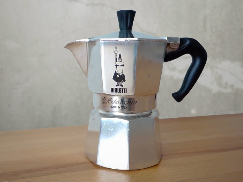 Front view of the Bialetti Moka Express, sitting on a wooden table