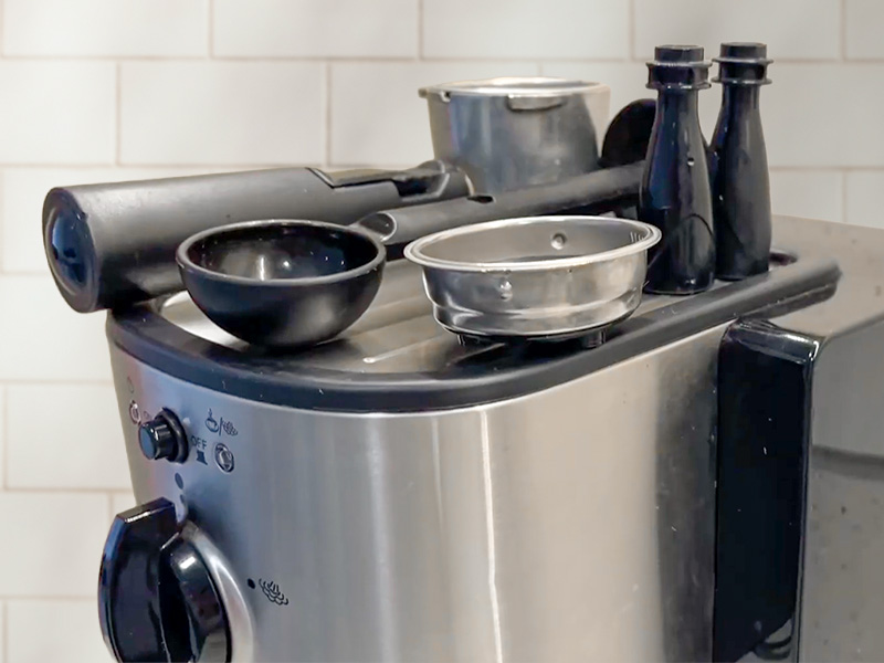 Portafilter and accessories for the Capresso EC100 sitting on the warming platform on top of the machine