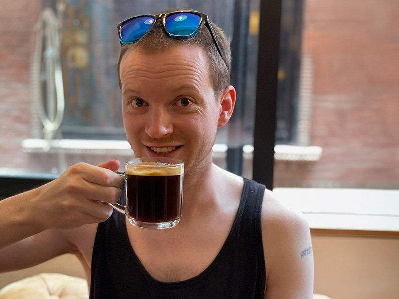 Matt drinking a red eye coffee with sunglasses on his head