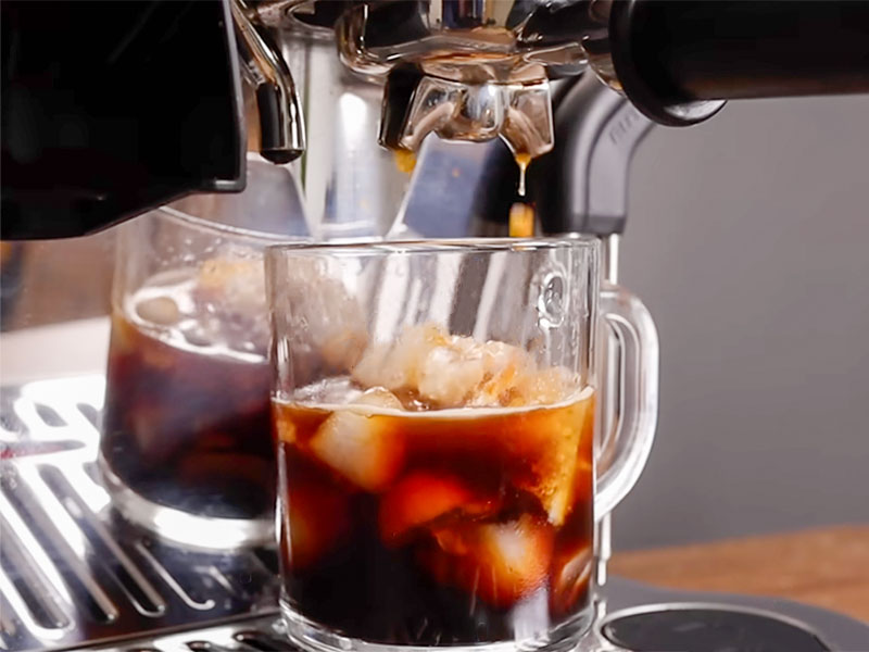 Freshly made cold brew (coffee over ice) on the drip tray of DeLonghi La Specialista Touch