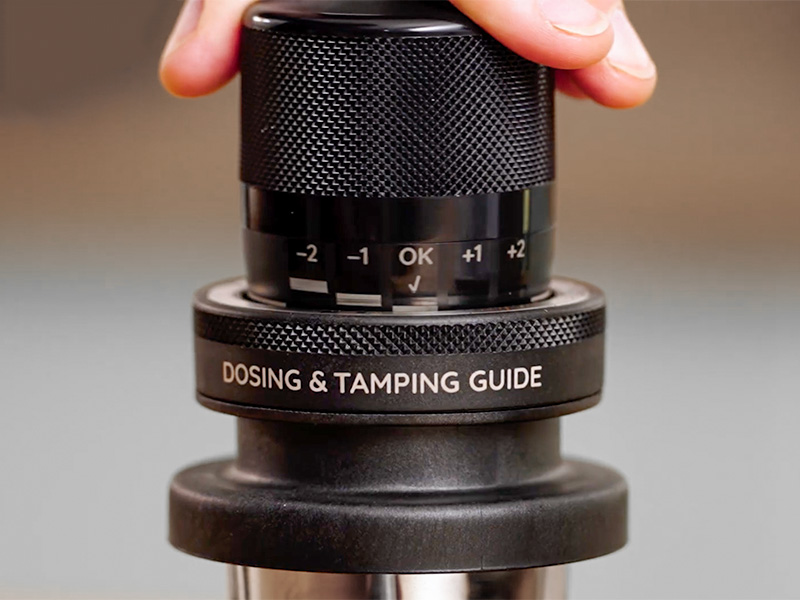 Close-up of the dosing and tamping guide being pressed down into the portafilter for DeLonghi La Specialista Touch