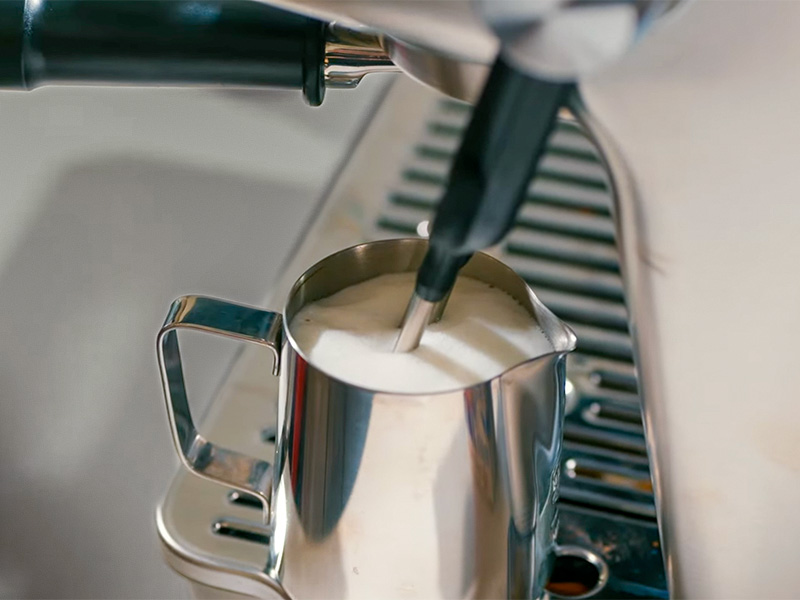 Top-down view of milk jug being auto steamed by the DeLonghi La Specialista Touch