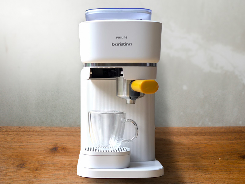 Front view of the Philips Baristina in white, with a glass cup sitting on the drip tray