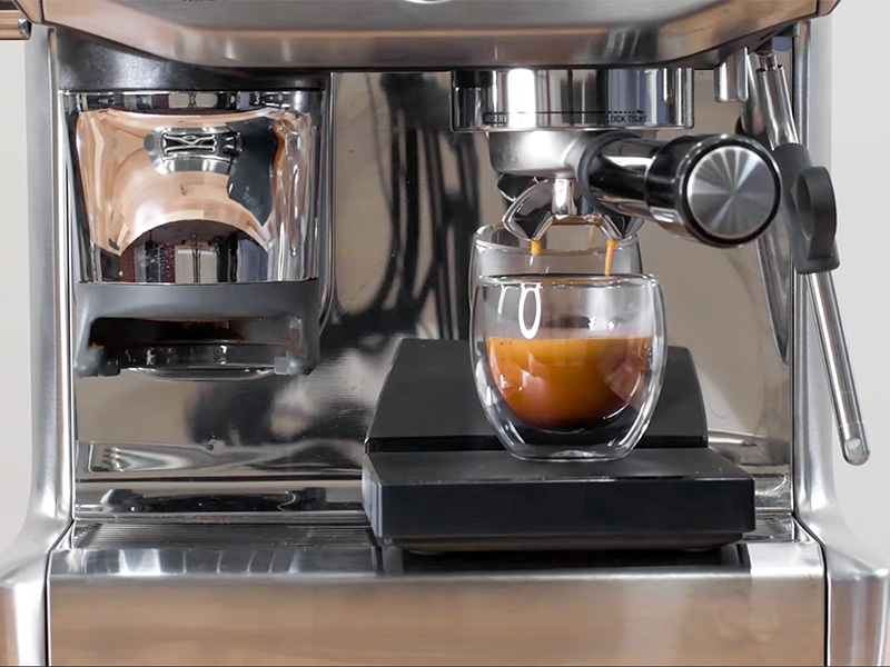 Close-up of a freshly made espresso shot sitting on a coffee scale on the drip tray of the Breville Barista Express Impress