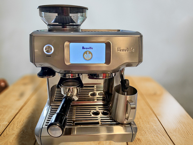 Front view of the Breville Barista Touch, turned on, sitting on a wooden table