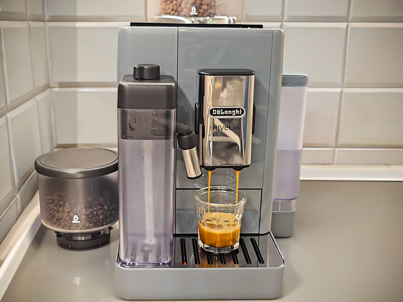 DeLonghi Rivelia mid-way through making an espresso shot, the spare bean hopper is sitting beside the machine