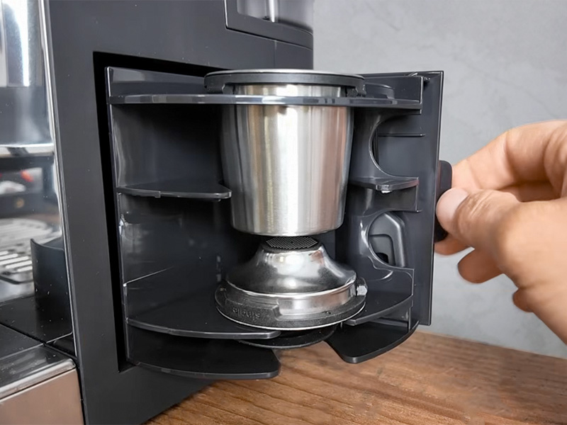 Hand opening the accessories storage compartment at the back of the Ninja Luxe Cafe Pro