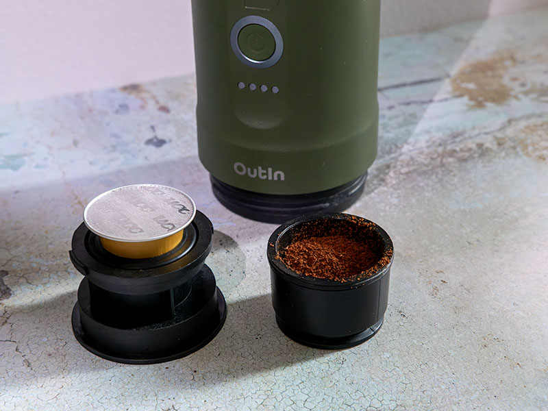 Two baskets for the OutIn Nano (forest green version in background), one with an original Nespresso pod, the other filled with ground coffee