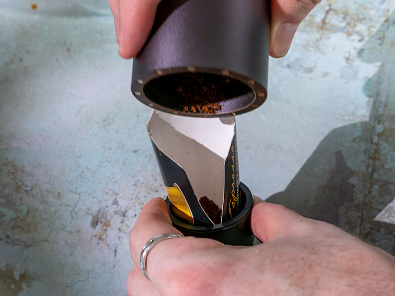 Using a piece of cardboard as a makeshift dosing funnel to transfer freshly ground coffee from grinder cup to the Outin Nano's basket