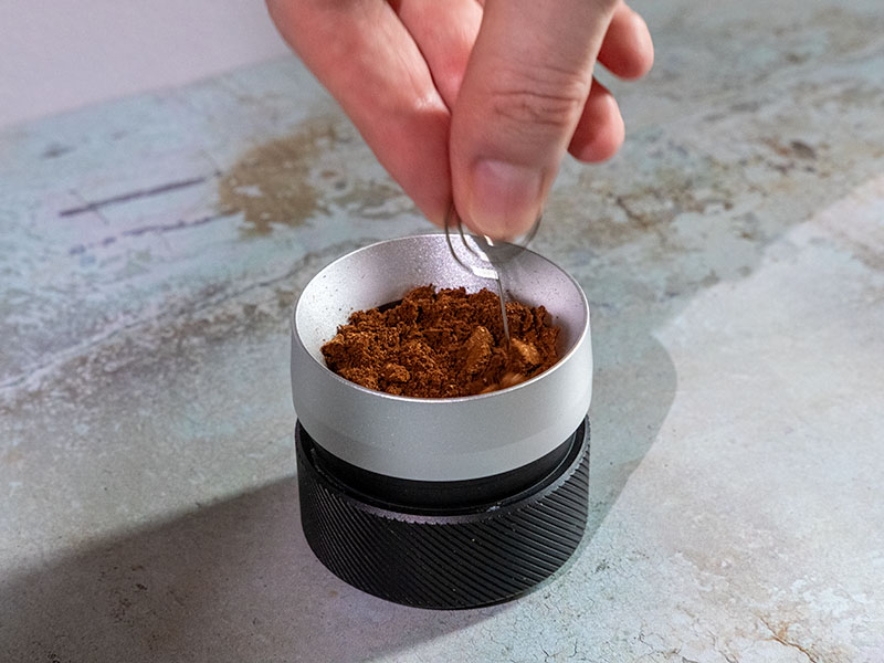 Using the WDT tool on ground coffee in the OutIn Basket Plus
