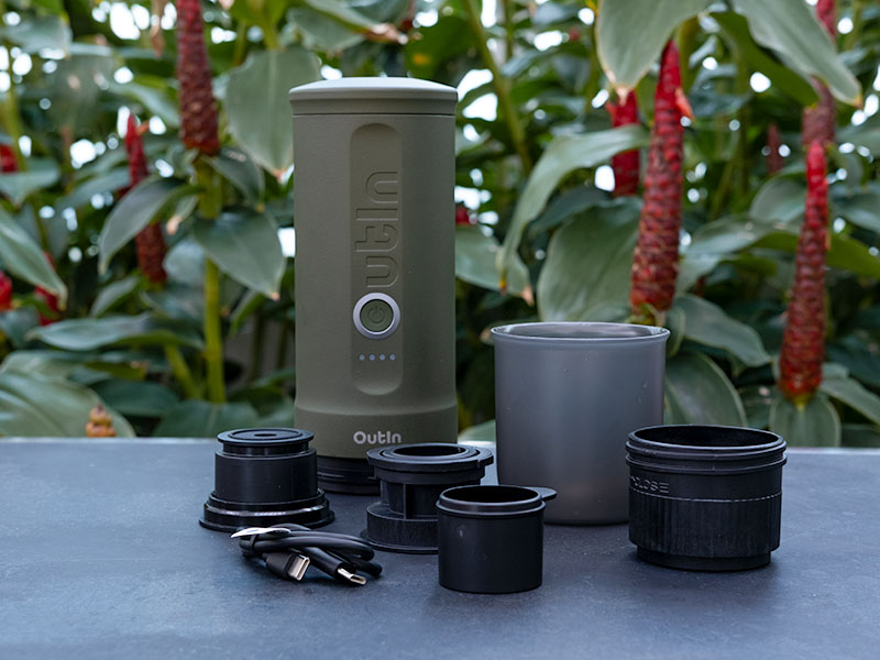 Outin Nano with all its included parts laid out on a table in front of a plant in the garden