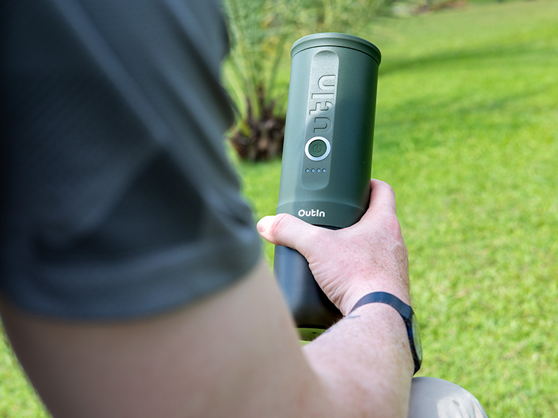 Man holding the OutIn Nano in front of him, dressed for a hike, with the grass around him