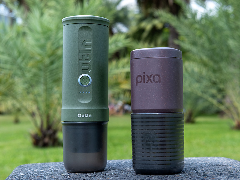 OutIn Nano and Wacaco Pixapresso standing beside each other on a stone bench with trees in the background