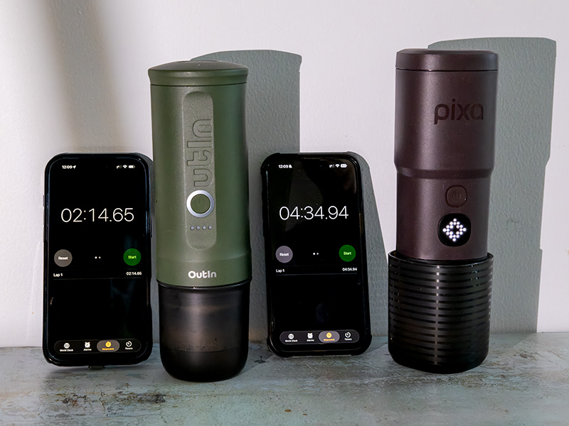 The Outin Nano and Wacaco Pixapresso sitting side-by-side with phone displaying stopwatch for how long it took the water to heat up from room temperature (2min 14 vs 4 min 34)