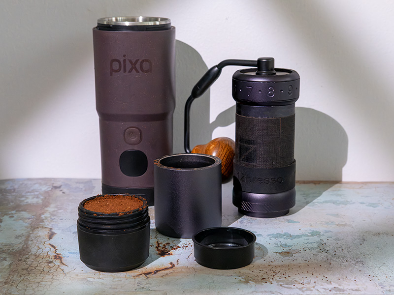Wacaco Pixapresso on table with full grounds basket, dosing funnel, and 1Zpresso J ultra grinder