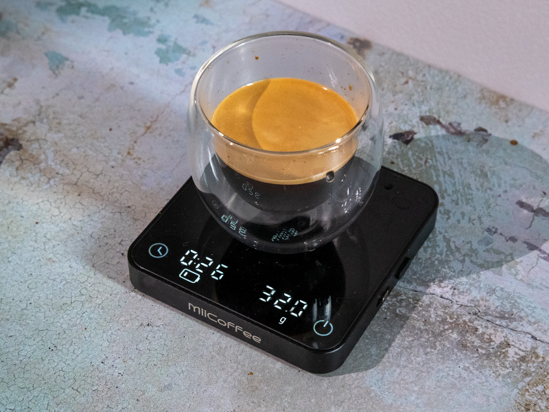 Fresh espresso with crema sitting on MiiCoffee scale, showing 32g in 26 seconds
