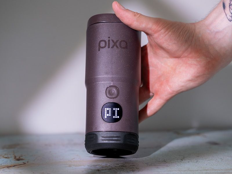 PI (pre-infusion) setting on the small touchscreen of the Pixapresso, held up by a man's hand