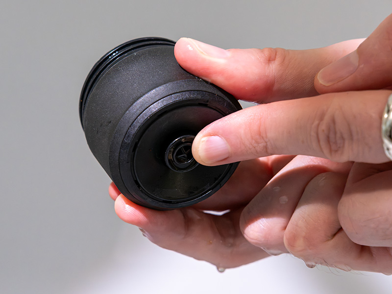 Finger pointing to the bottom of the Pixapresso's grounds basket, where you press for puck removal